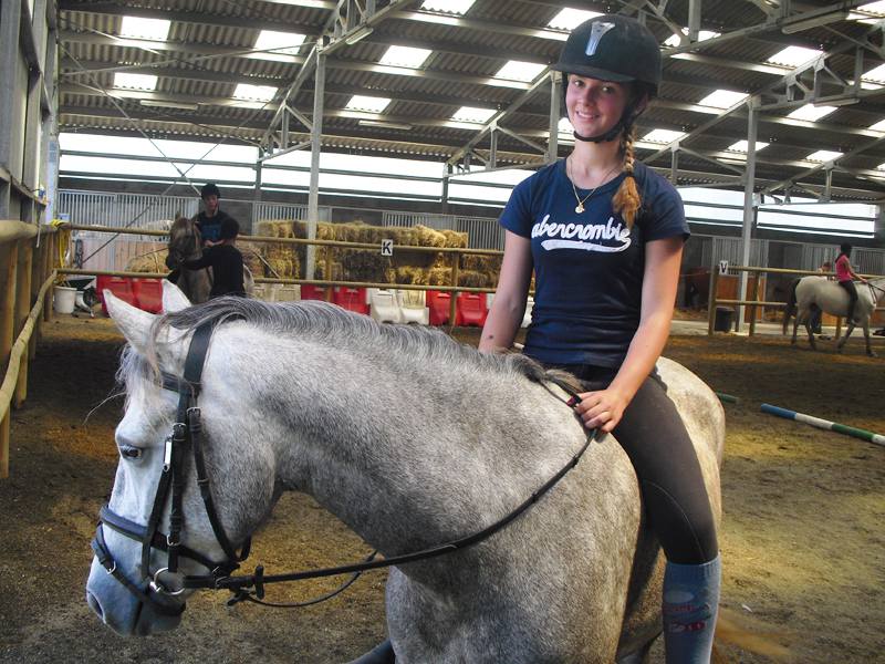 Jeune fille montant à cheval en manège