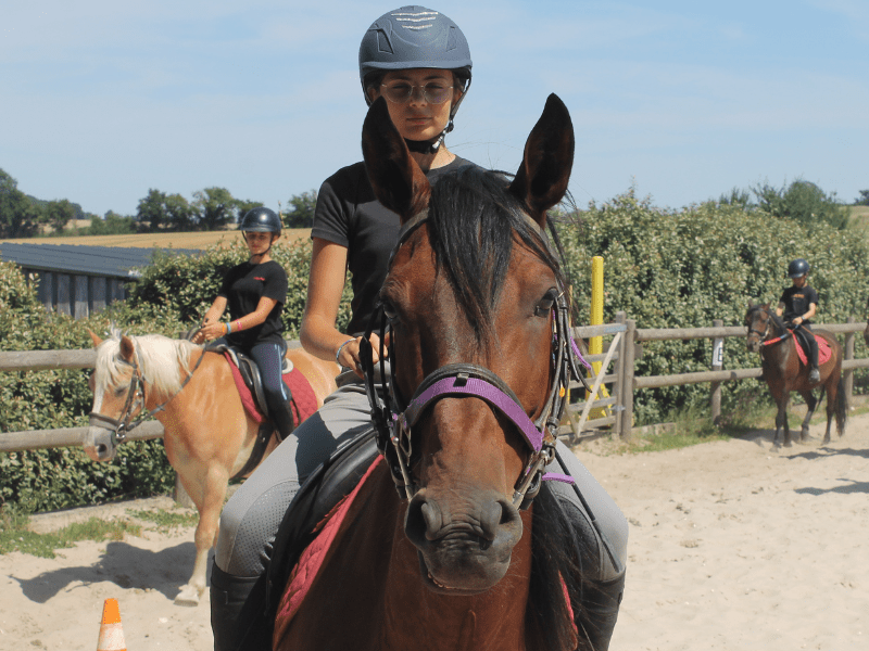 Vue sur une jeune à cheval durant sa colo de vacances Equitation au domaine de l'Espérance
