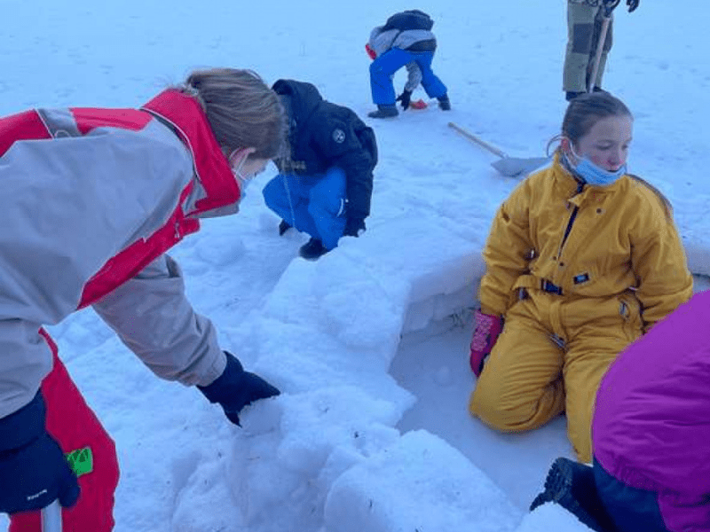 Jeunes enfants qui construisent un igloo durant  leur colo de vacances Ski mountain adventure