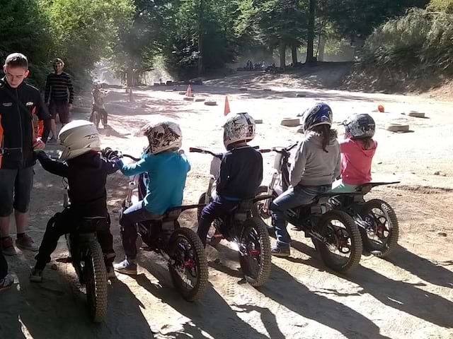 Animateur apprenant aux enfants à faire de la moto en colo