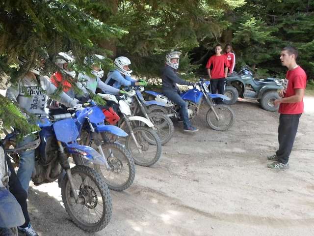 Animateur de colonie de vacances apprenant aux enfants à conduire une moto