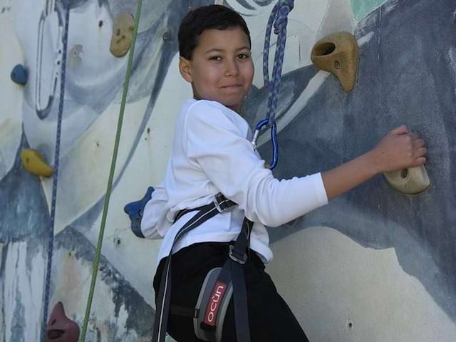 Jeune garçon en colo de vacances qui s'apprête à grimper le mur d'escalade à Monistrol lors de son séjour Quad et Cross