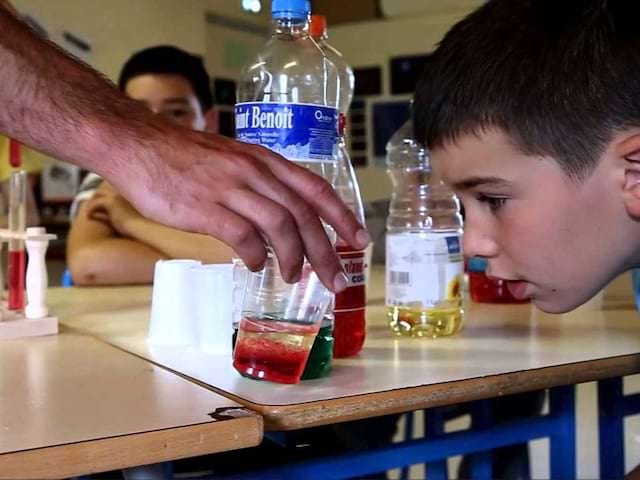 Enfant observant une expérience scientifique en colonie de vacances