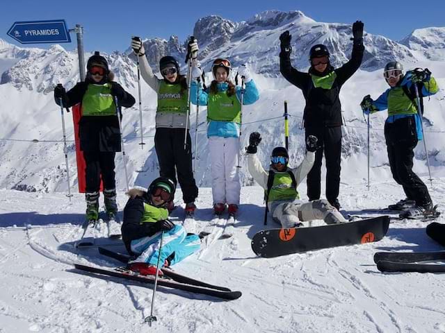 Groupe d'enfants pratiquant divers sports d'hiver en colo