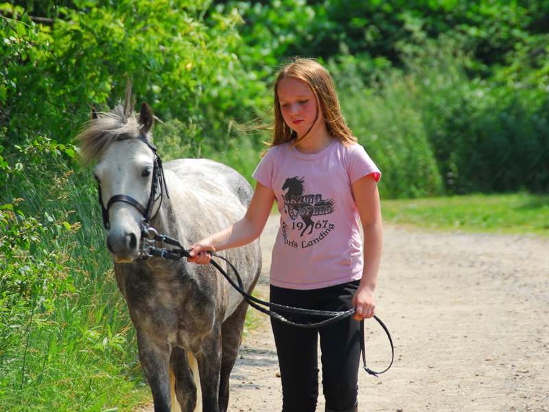 Jeune fille en balade avec son cheval en colonie de vacances