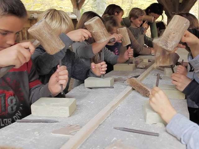 Enfants apprenant à tailler la pierre comme au moyen age en colonie 