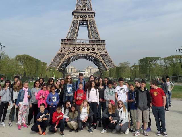 Groupe d'enfants et ados posant devant la tour eiffel lors d'une colonie de vacances au printemps