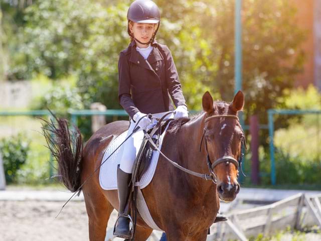 Jeune fille à cheval en stage sportif