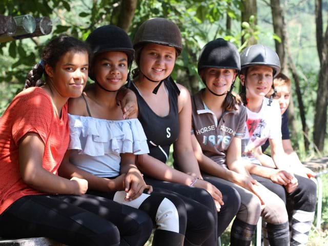 Groupe de jeunes filles pratiquant l'équitation en colo