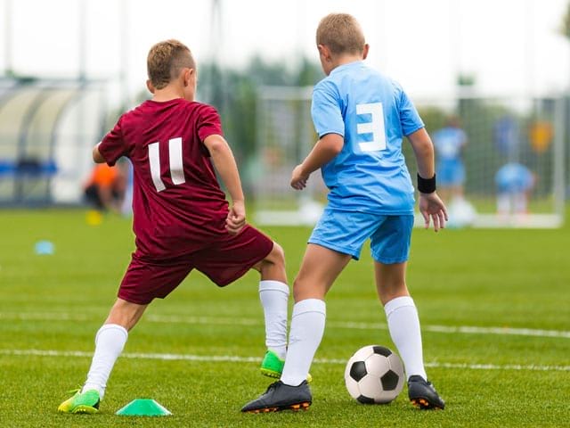 Enfant jouant au football en stage sportif