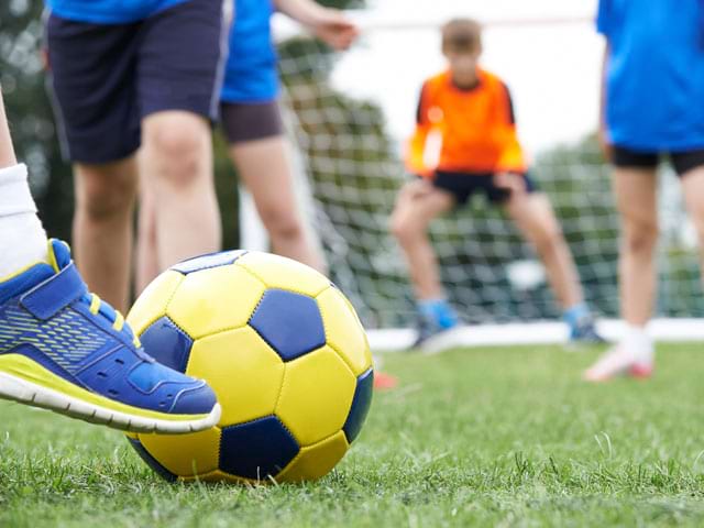 Ados jouant au football en stage sportif 