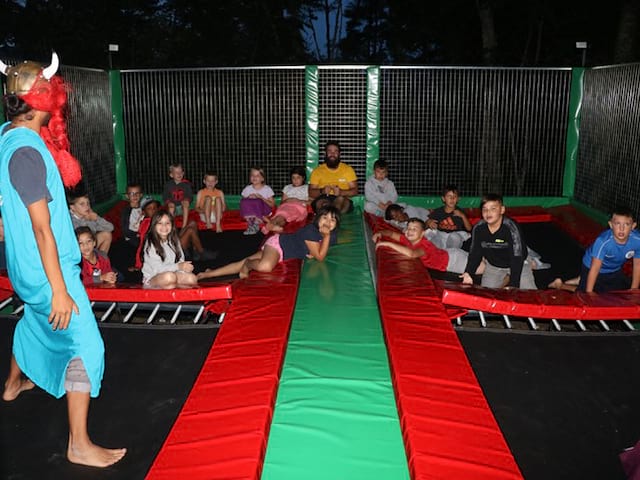 Enfants et leur animateur de colonie de vacances faisant du trampoline