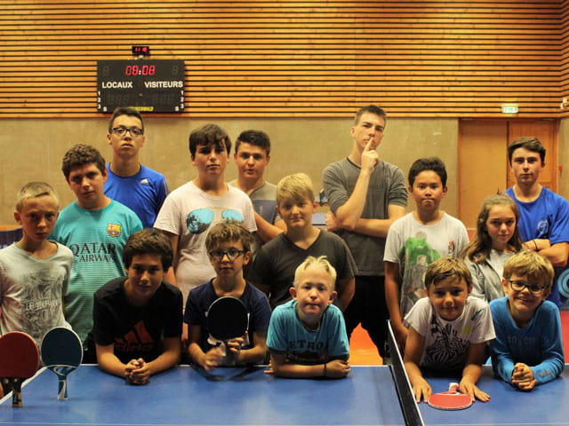 Groupe d'enfants pratiquant le tennis de table en colo