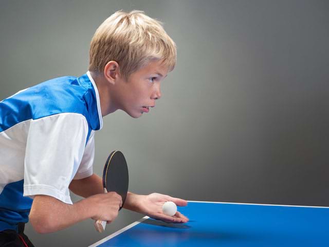 Enfant qui pratique le tennis de table à haut niveau en colo