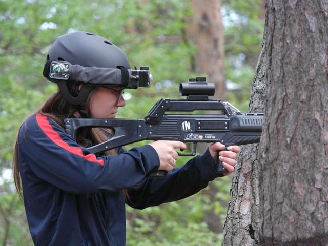 portrait d'une ado faisant du laser game en extérieur en colonie de vacances