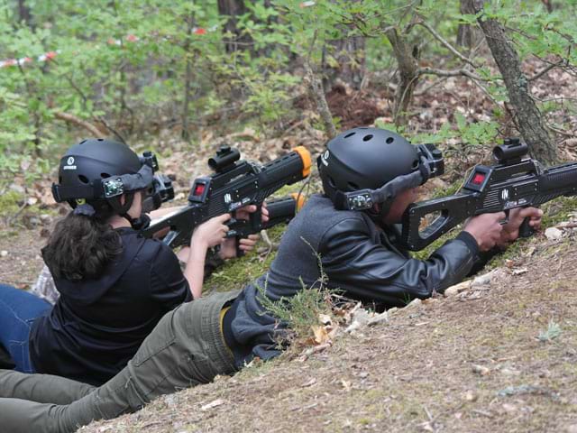 Enfants pendant une partie de laser game extérieur en colonie de vacances