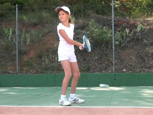 Jeune fille se perfectionne au tennis pendant un stage sportif