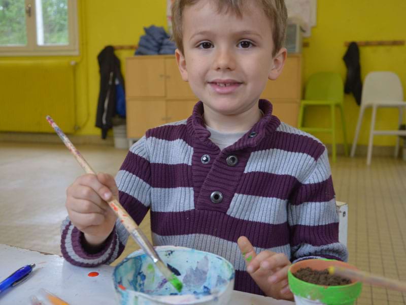 enfant faisant de la peinture en colonie de vacances à la ferme