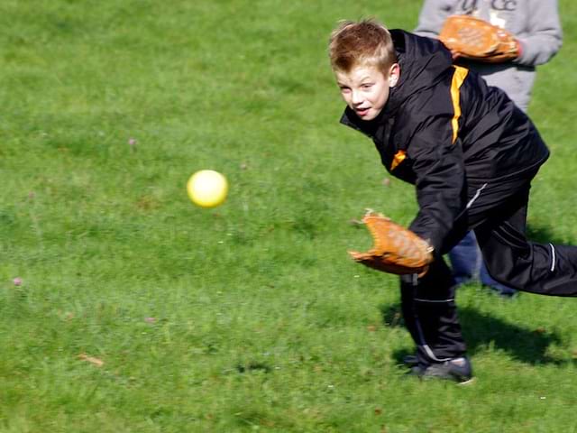 Enfant en train d'attraper la balle au baseball en colonie de vacances pour apprendre l'anglais en France