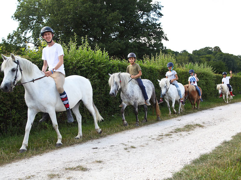 groupe d'enfants en randonnée à cheval en colonie de vacances pour apprendre l'anglais en France