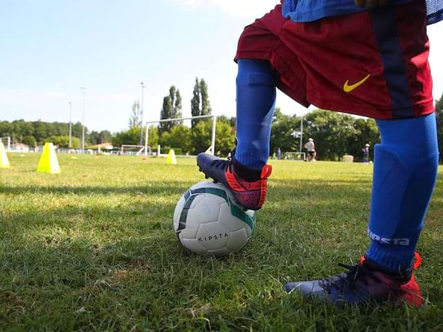 Vue sur les pieds d'un enfant portant une tenue de football en colonie de vacances multisports au printemps