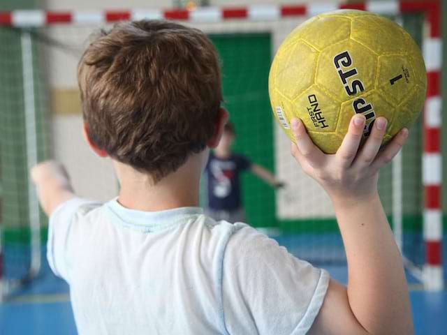 Enfant jouant au handball en colonie de vacances multisports au printemps