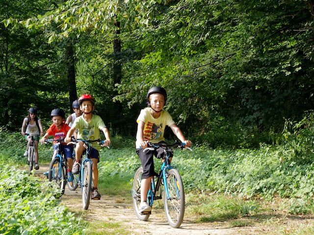 groupe d'enfants en randonnée à vélo en colonie de vacances multisports au printemps