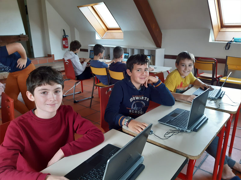 groupe d'enfants sur ordinateurs apprenant la programmation en colo