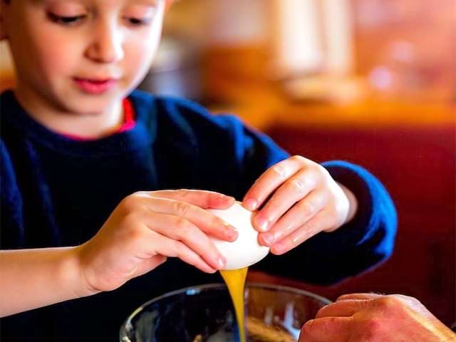 jeune enfant cassant un oeuf en colo cuisine ce printemps