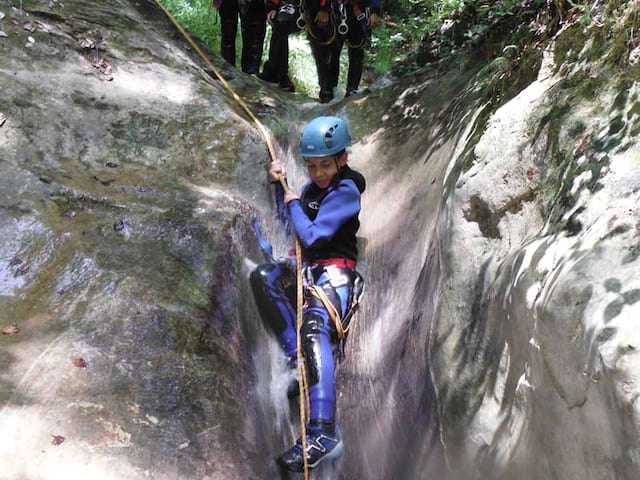 Groupe d'enfants descendant d'un toboggan naturel pendant une activité de canyoning en colonie de vacances