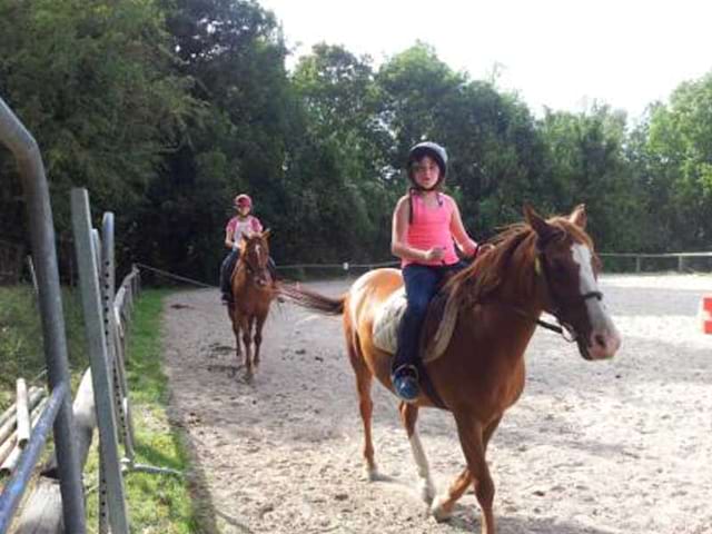 Enfants faisant de l'équitation dans un manège en colonie de vacances