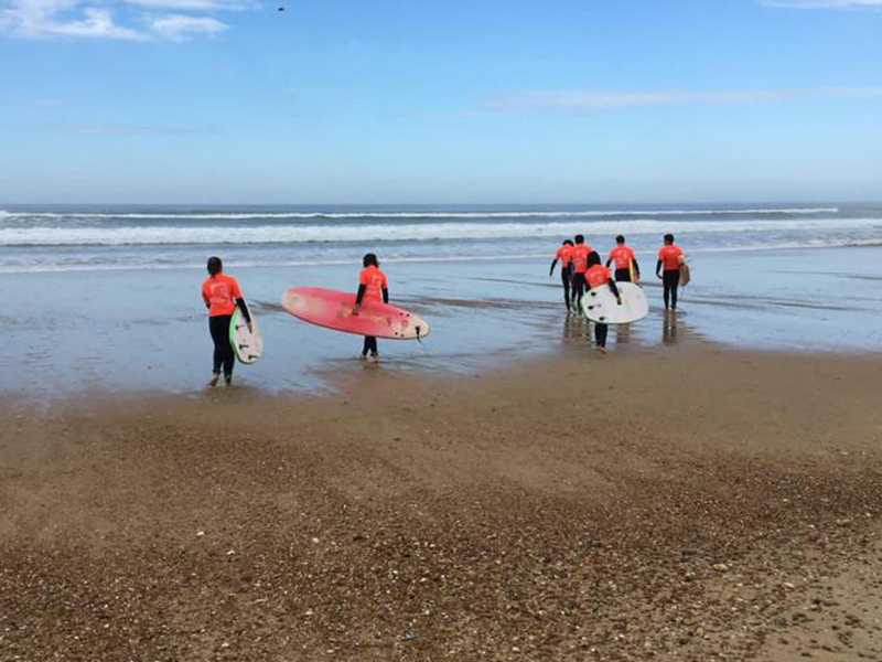 groupe d'ados apprenant à faire du surf en colonie de vacances ce printemps