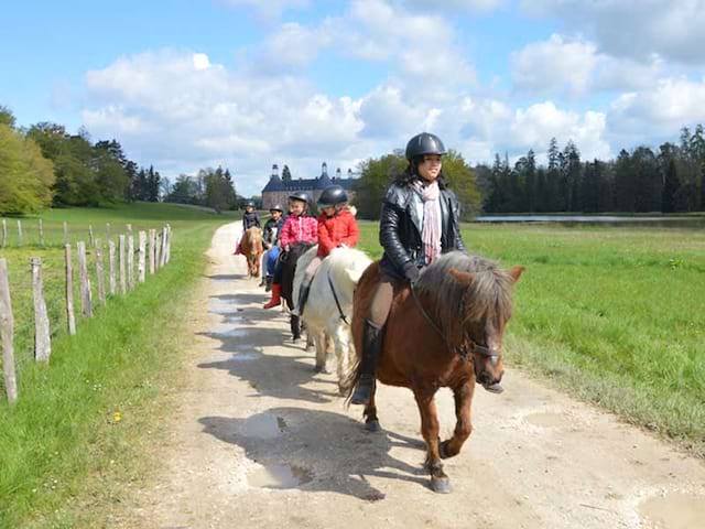 groupe d'enfants apprenant à faire du poney en colonie de vacances