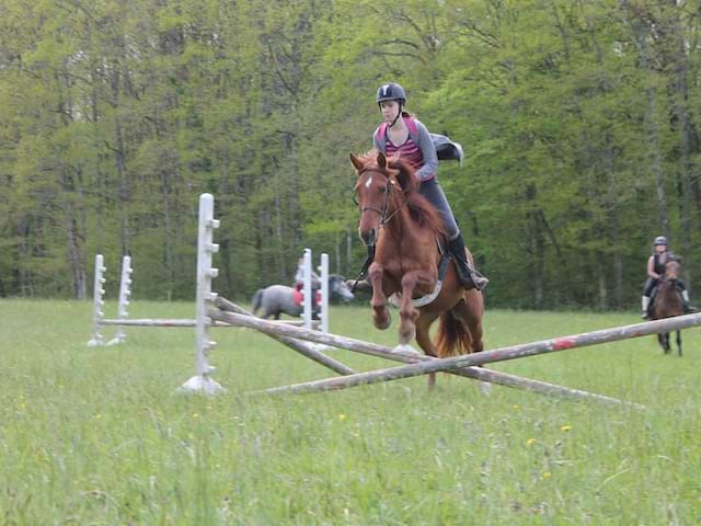 Enfant faisant des courses d'obstacle à cheval en colonie de vacances au printemps