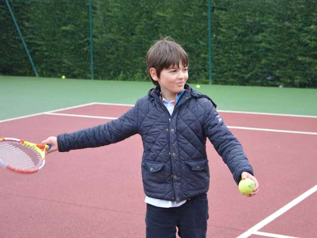 Enfant apprenant à faire du tennis en colonie de vacances multiactivités