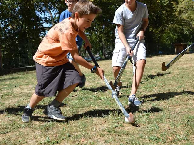 Enfants jouant au hockey sur gazon en colonie de vacances d'été