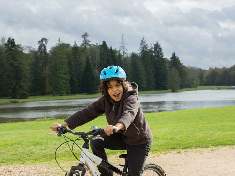 enfant faisant du vélo en colonie de vacances à la campagne cet été