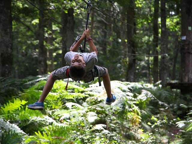 adolescente faisant de la tyrolienne en colonie de vacances accrobranche