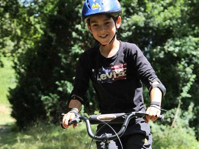 enfant faisant de la trottinette tout terrain en colonie de vacances cet été