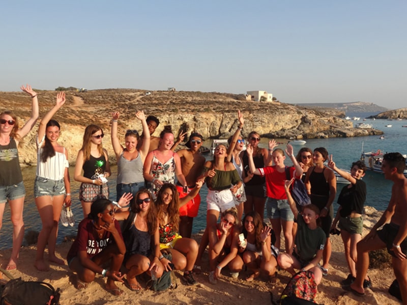 Tous les jeunes ados lèvent les bras au bord de la plage maltaise lors d'une colo de vacances linguistique à Malte durant le printemps