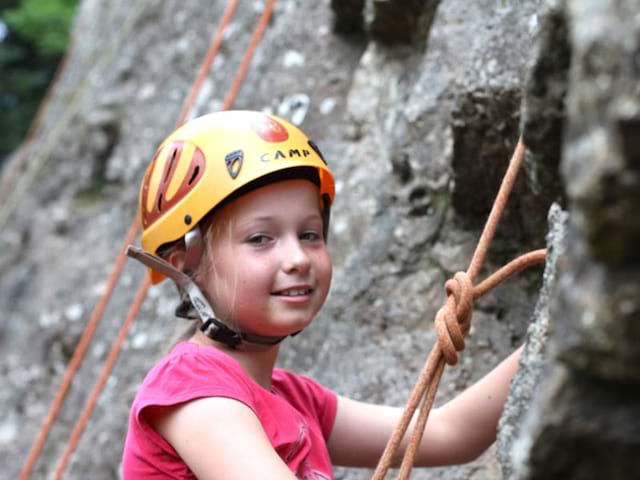 Vue sur une petite fille qui escalade un mur lors d'activités durant la colo Artistes en herbe