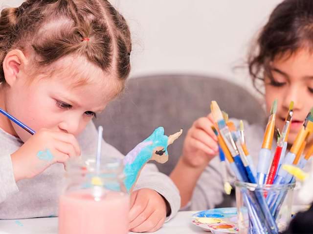 Enfants qui font du bricolage et qui décorent des objets lors d'une colonie de vacances artistique