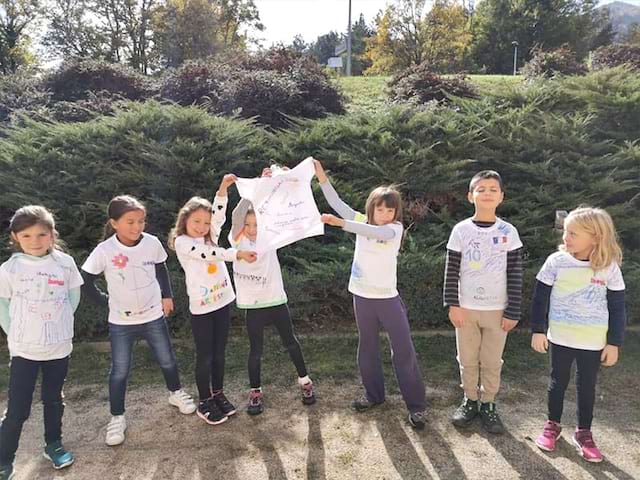 Vue sur des enfants qui tendissent un tee shirt qu'ils ont eux mêmes décoré lors d'une colo de vacances artistique