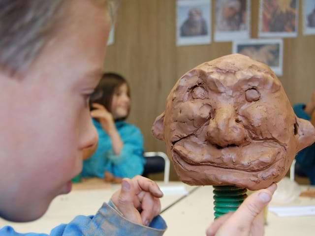 Jeune enfant concentré qui fait de la poterie en colonie de vacances Artistes en herbe 