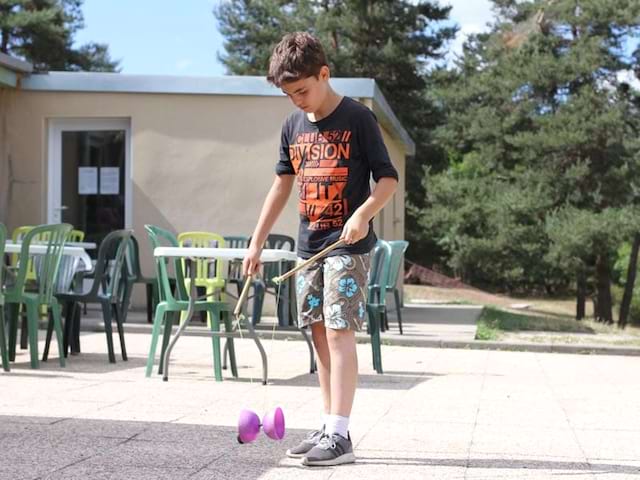 Jeune enfant qui fait du diabolo lors de sa colonie de vacances Artistes en herbe