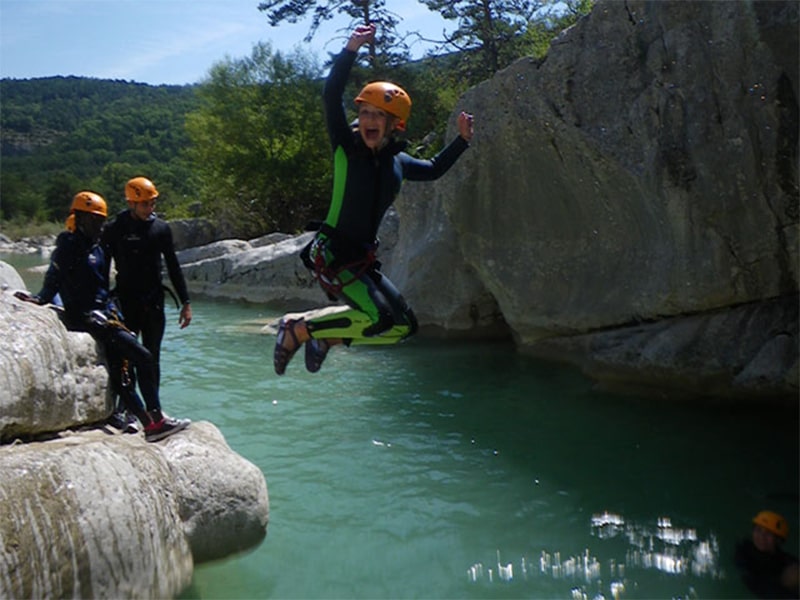 Jeunes garçons qui sautent d'un rocher lors d'une session canyoning lors d'une colonie de vacances en Corse durant le printemps