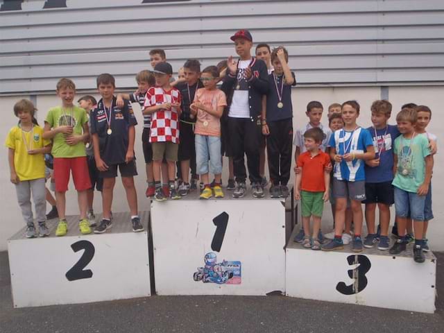 Podium en colonie de vacances où les jeunes pilotes célèbrent leur course automobile 