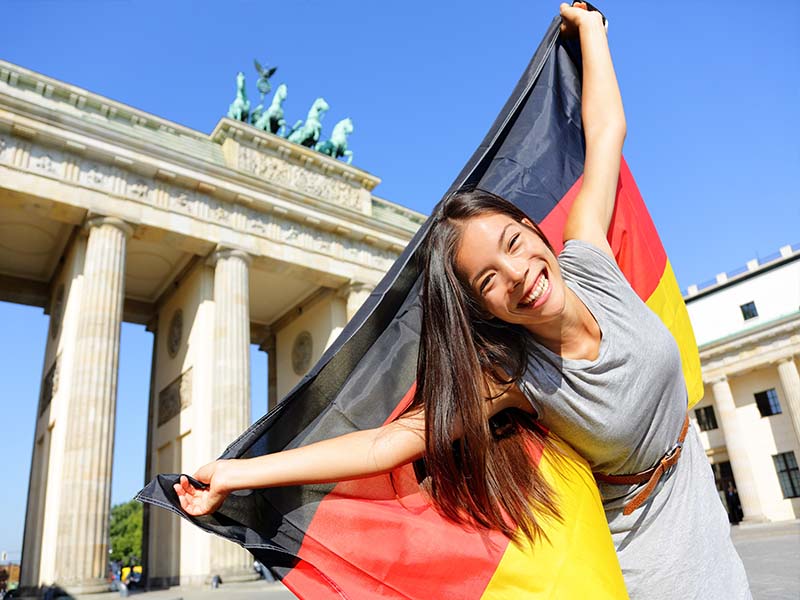 Jeune ado qui brandit le drapeau allemand et qui profite de sa colo de vacances à Berlin