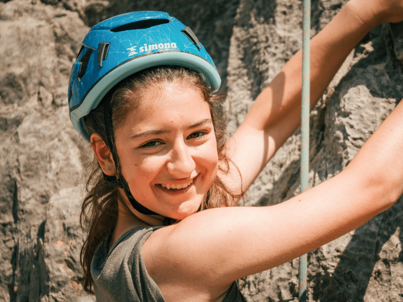 Jeune fille qui escalade une falaise lors de sa colonie de vacances Cinema durant le printemps