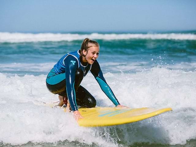 Surfeuse ado qui apprend à pratiquer le surf au Maroc lors d'une colonie de vacances au printemps